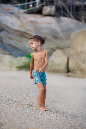 boy standing on the sand by the seaの写真素材