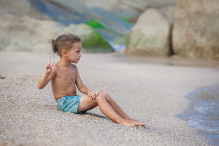 boy sitting on the sand by the seaの写真素材