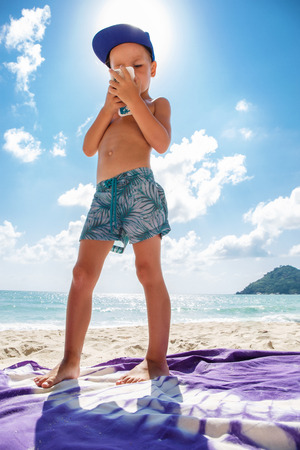 Cute boy is playing in a  mobile phone on the beachの写真素材