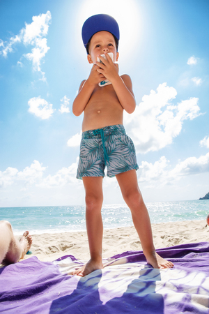 Cute boy is playing in a  mobile phone on the beachの写真素材