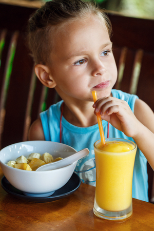 beautiful boy is having breakfast with juice and porridgeの写真素材