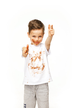 little boy with face and hands in chocolateの写真素材