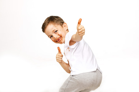 little boy with face and hands in chocolateの写真素材