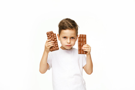 little boy with two chocolates on a white backgroundの写真素材