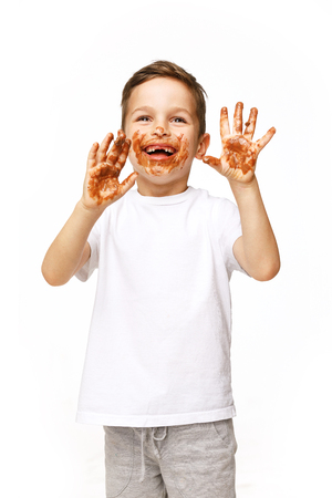 little boy with face and hands in chocolateの写真素材