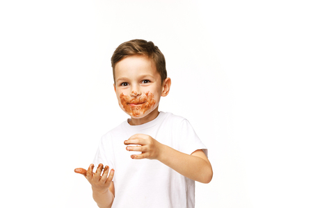 little boy with face and hands in chocolateの写真素材