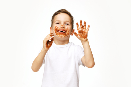little boy with face and hands in chocolateの写真素材