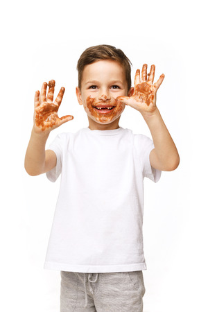 little boy with face and hands in chocolateの写真素材