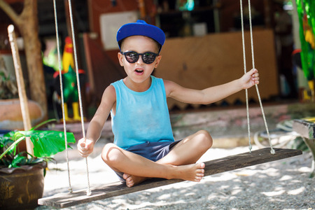 little boy is sitting on a swingの写真素材