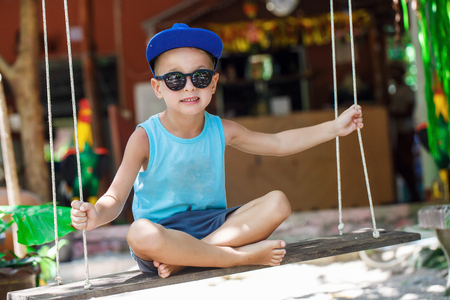 little boy is sitting on a swingの写真素材
