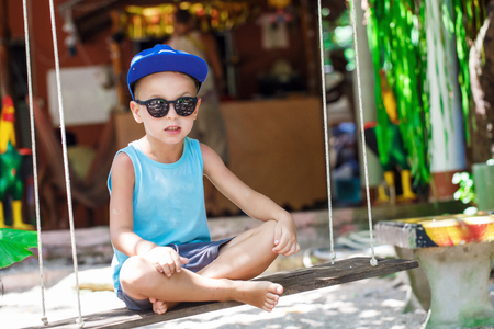 little boy is sitting on a swingの写真素材