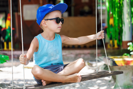 little boy is sitting on a swingの写真素材