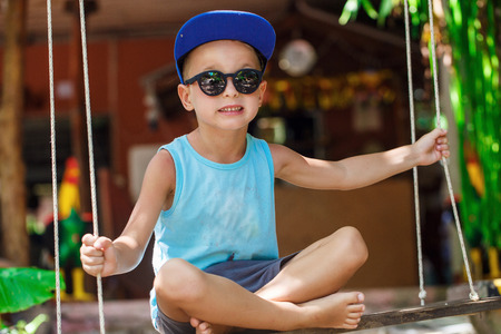 little boy is sitting on a swingの写真素材