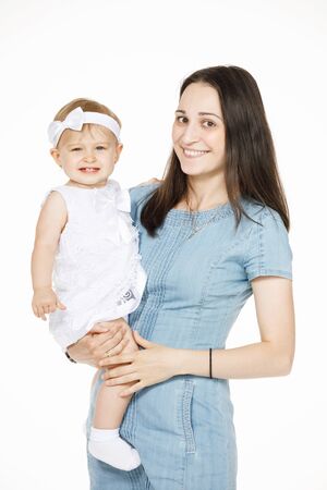 little girl in white in her mothers armsの写真素材