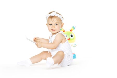 little girl all in white with tablet and toyの写真素材
