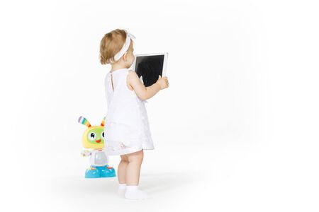 little girl all in white with tablet and toyの写真素材