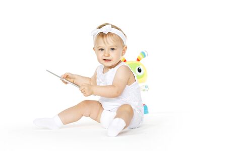 little girl all in white with tablet and toyの写真素材