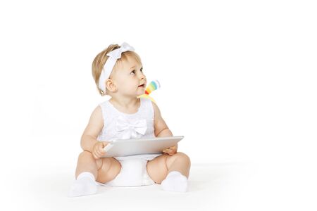 little girl all in white with tablet and toyの写真素材