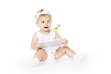 little girl all in white with tablet and toyの写真素材