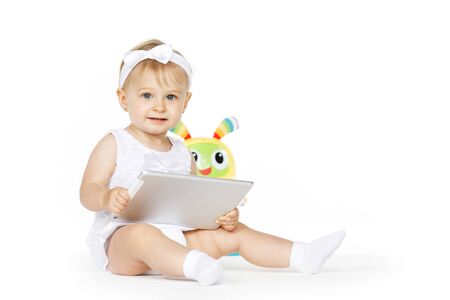 little girl all in white with tablet and toyの写真素材