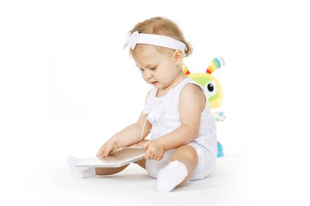 little girl all in white with tablet and toyの写真素材