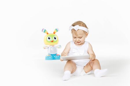 little girl all in white with tablet and toyの写真素材
