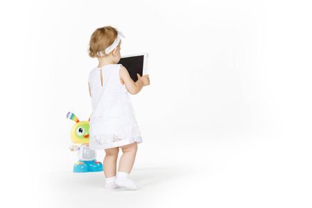 little girl all in white with tablet and toyの写真素材