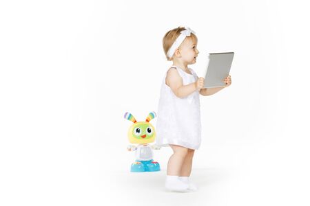 little girl all in white with tablet and toyの写真素材