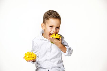 handsome boy in a white shirt is eating mangoの写真素材