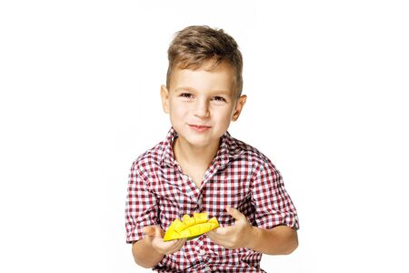 handsome boy in a red shirt is eating mangoの写真素材
