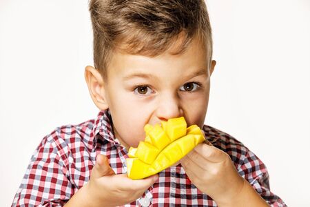 handsome boy in a red shirt is eating a mango