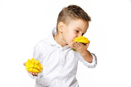 handsome boy in a white shirt is eating a mangoの写真素材
