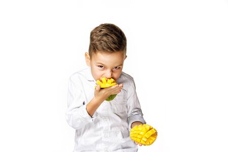 handsome boy in a white shirt is eating a mangoの写真素材