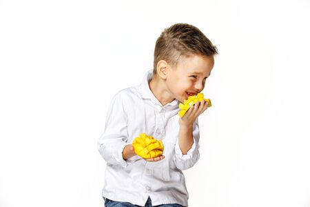 handsome boy in a white shirt is eating a mangoの写真素材