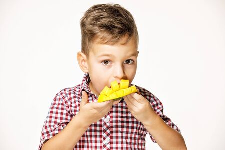 handsome boy in a red shirt is eating a mangoの写真素材