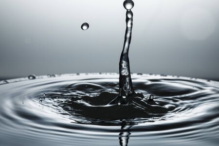 drop of water falling down in the waterの写真素材