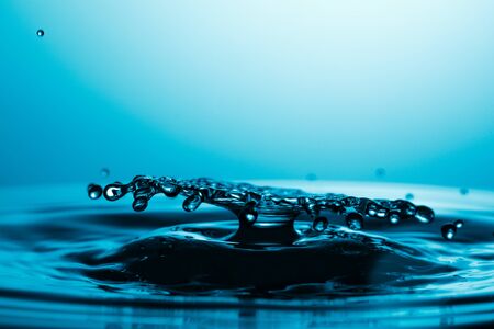 drop of water falling down in the waterの写真素材