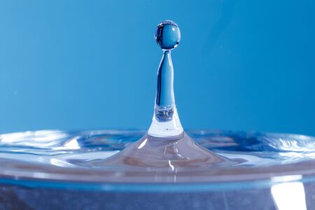 drop of water falling down in the waterの写真素材