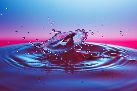 drop of water falling down in the waterの写真素材