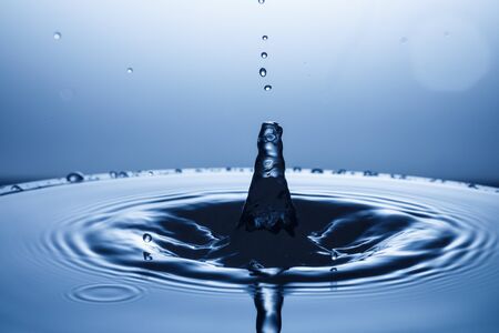 drop of water falling down in the waterの写真素材