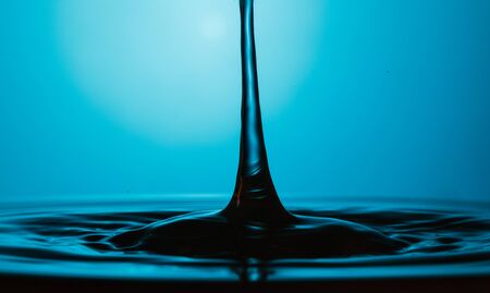 drop of water falling down in the waterの写真素材