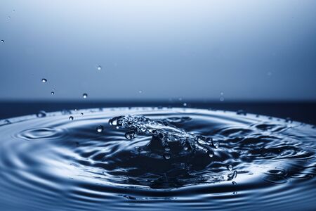 drop of water falling down in the waterの写真素材