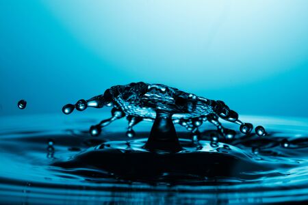 drop of water falling down in the waterの写真素材