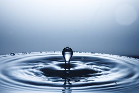 drop of water falling down in the waterの写真素材