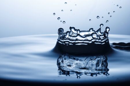 drop of water falling down in the waterの写真素材