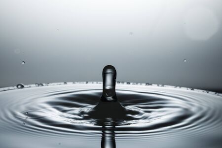drop of water falling down in the waterの写真素材