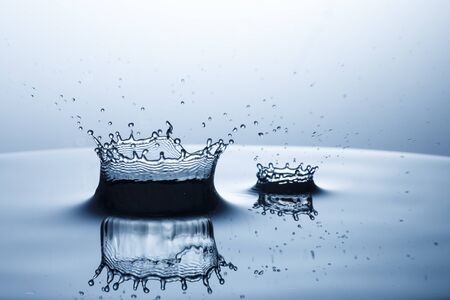 drop of water falling down in the waterの写真素材