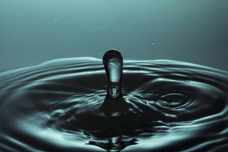 drop of water falling down in the waterの写真素材