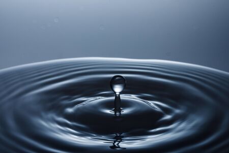 drop of water falling down in the waterの写真素材