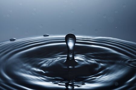 drop of water falling down in the waterの写真素材